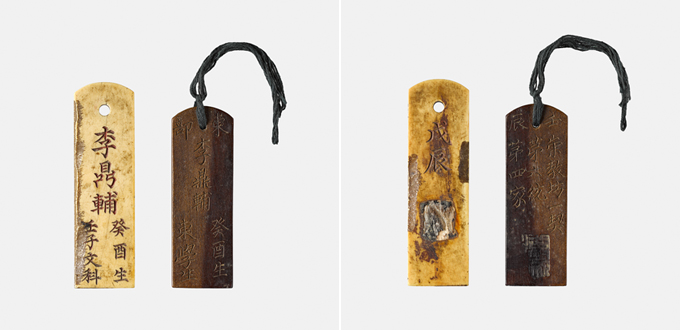 Two Joseon identity tags shown front and back: a pale ivory tag inscribed with the name Yi Jeong-bo, his birth year and his examination year, and a darker wooden tag on a cord.